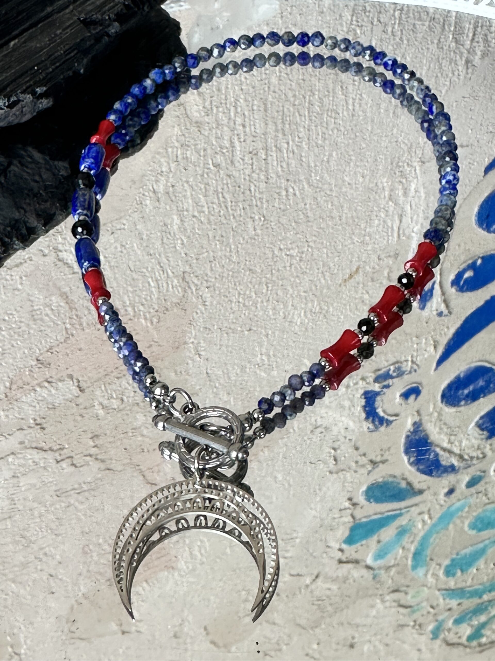 Naszyjnik z lapis lazuli, turmalinu i czerwonego korala z zawieszką w kształcie księżyca – biżuteria symbolizująca kobiecą intuicję, przemianę i ochronę energetyczną.
